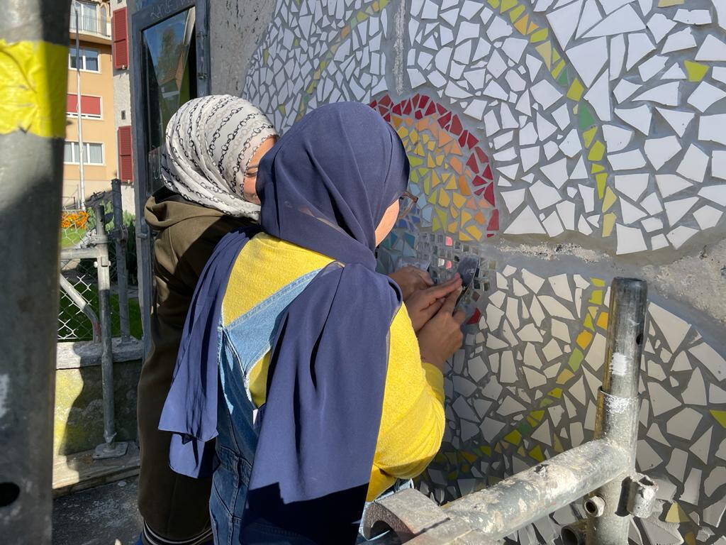 Zwei Frauen arbeiten an einem Wandmural