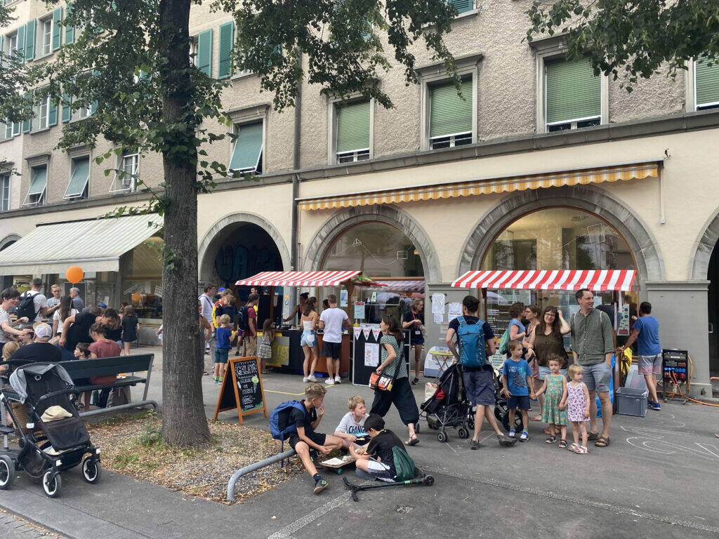 Lebendige Neubrückstrasse mit Ständen und vielen Menschen.